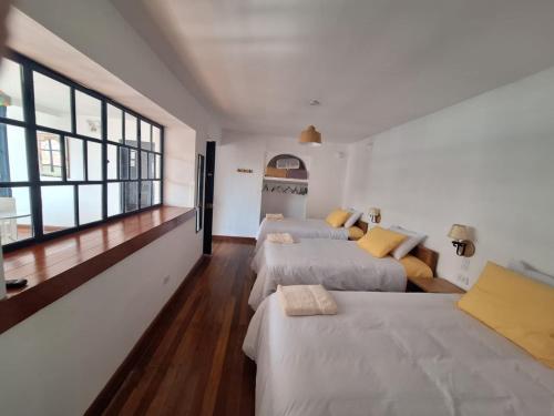a room with three beds and a couch and windows at Illa B&B in Cusco