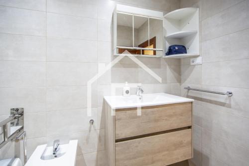 uma casa de banho branca com um lavatório e um espelho em Ático Quintana II - con terraza, en el centro con Wifi y garaje em Oviedo
