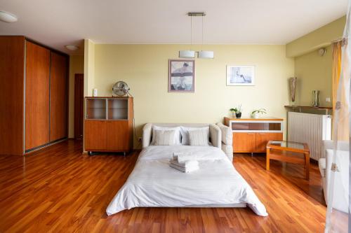 a bedroom with a bed with white sheets and wooden floors at Aleja Wyścigowa Comfort Apartment in Warsaw
