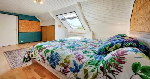 um quarto com uma cama com um edredão floral e uma janela em Maison 4 personnes, Moëlan sur mer, proche plages em Moëlan-sur-Mer