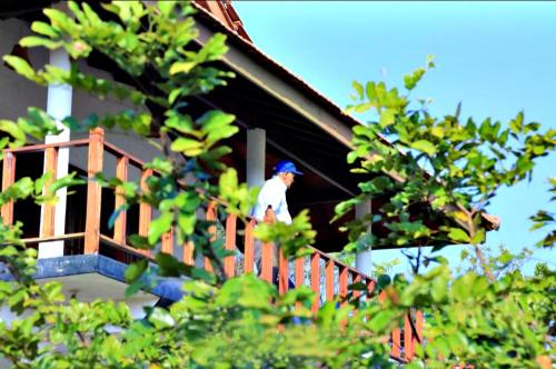 un hombre parado en el porche de una casa en Pearl Cave Cabanas & Resturant, en Tangalle