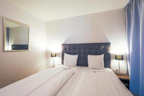 a bedroom with a large white bed with a blue headboard at Residence Bellevue - incl Summercard in Zell am See