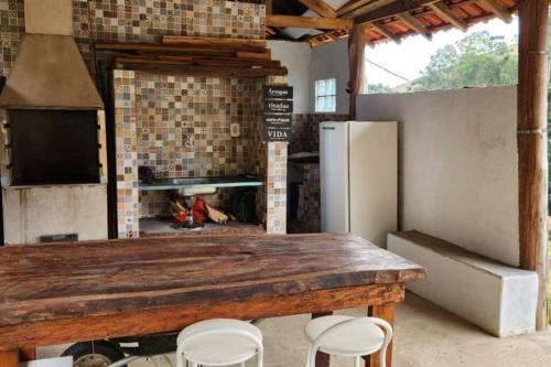 a kitchen with a fireplace and a table and stools at Sitio Cachoeira da Gomeira in Passa Quatro