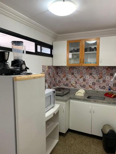 een keuken met witte kasten en een magnetron bij Adriana Flats - Sem vista mar e sem varanda in Fortaleza
