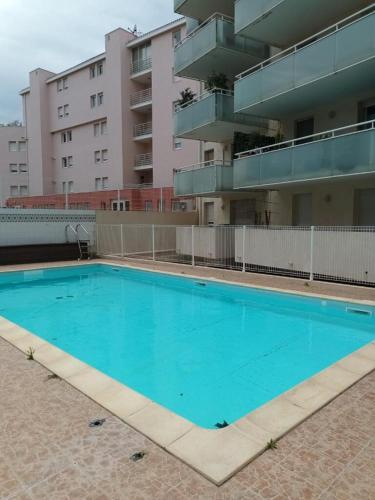 une piscine vide en face d'un bâtiment dans l'établissement Appartement T2, climatisé, wifi, parking et piscine privés, à Sète