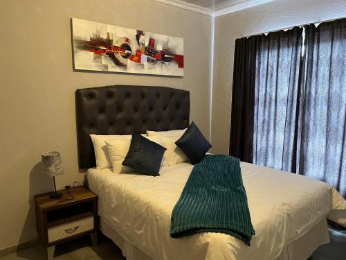 a bedroom with a bed with a green blanket on it at Mafikeng Boutique Lodge in Mahikeng