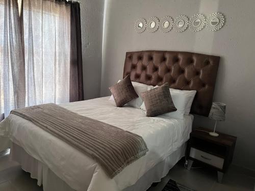 a bedroom with a large bed with a brown headboard at Mafikeng Boutique Lodge in Mahikeng