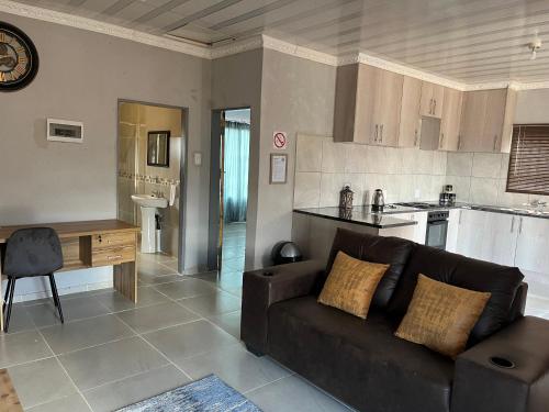 a living room with a couch and a kitchen at Mafikeng Boutique Lodge in Mahikeng
