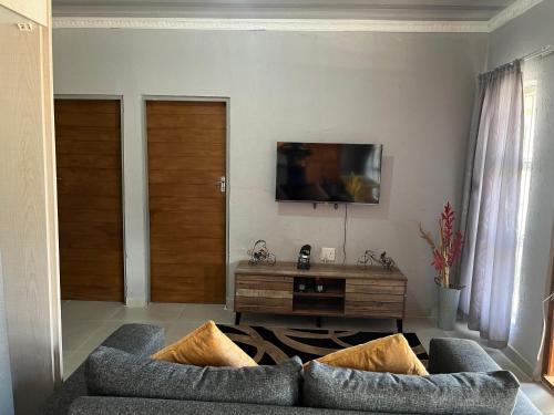 a living room with two couches and a tv at Mafikeng Boutique Lodge in Mahikeng