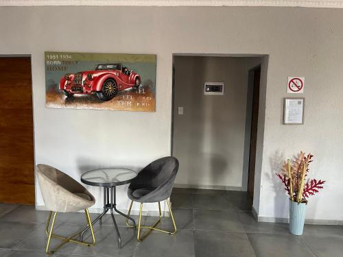 a room with a table and two chairs and a red car painting at Mafikeng Boutique Lodge in Mahikeng