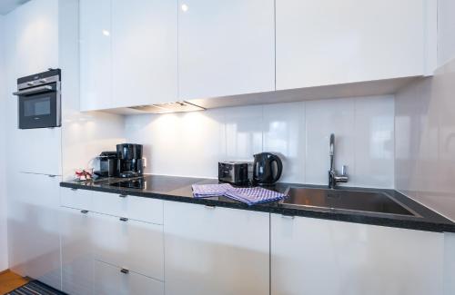 a kitchen with white cabinets and a sink at Residence Bellevue - incl Summercard in Zell am See