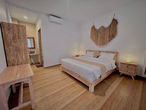 een slaapkamer met een wit bed en een houten vloer bij Nay's Homestay in Canggu