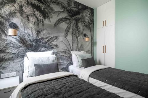 - 2 lits dans une chambre ornée d'une fresque murale de palmiers dans l'établissement The Green Loft - Eiffel Tower - Paris 15, à Paris