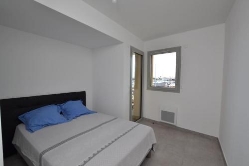 une chambre avec un lit avec des oreillers bleus et une fenêtre dans l'établissement Le Danieli sur les quais, au Grau-du-Roi