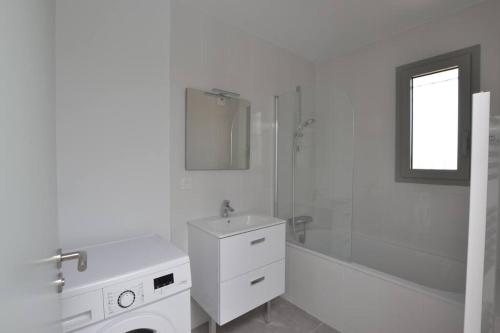 une salle de bain blanche avec un lavabo et une douche dans l'établissement Le Danieli sur les quais, au Grau-du-Roi