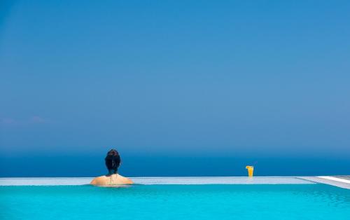 a person standing on a rock in the water at Eos Villa in Imerovigli