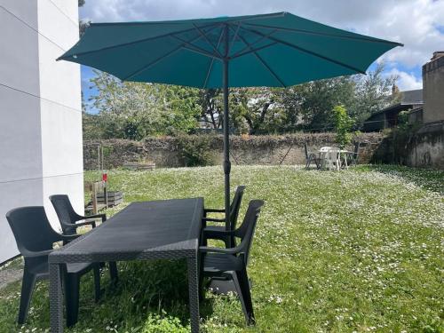 a black table and chairs with a green umbrella at T3 de 68m2 avec jardin, à 5mn gare et centre ville in Nantes