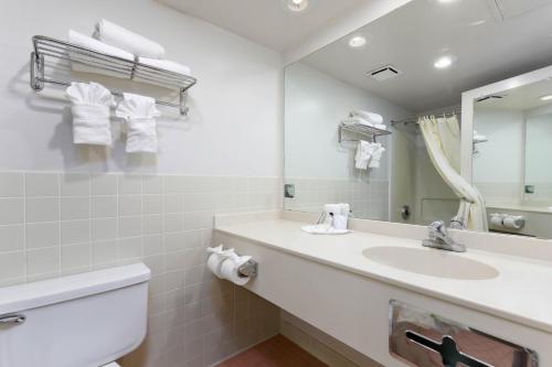 Baño blanco con lavabo y espejo en Studio 6 Suites Lake Havasu City AZ, en Lake Havasu City