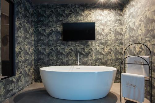 a bathroom with a tub and a tv on a wall at Il Pumo - Apulian Rooms Bari Savoia in Bari