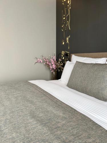 a bed with white sheets and a vase with flowers at Arka Art Hotel in Tirana
