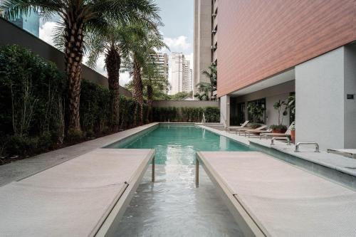 a swimming pool in a building with palm trees at Yume Vitrali Studios in Sao Paulo
