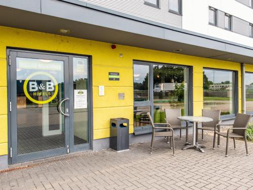 ein gelbes Gebäude mit einem Tisch und Stühlen im Freien in der Unterkunft B&B Hotel Erlangen in Erlangen