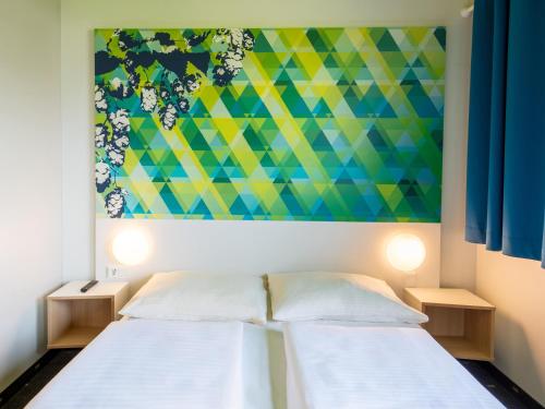 2 Betten in einem Zimmer mit Wandgemälde in der Unterkunft B&B Hotel Erlangen in Erlangen