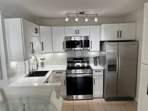 uma cozinha com armários brancos e um frigorífico de aço inoxidável em Beautiful studio(2325-1) - Walk to the beach em Fort Lauderdale