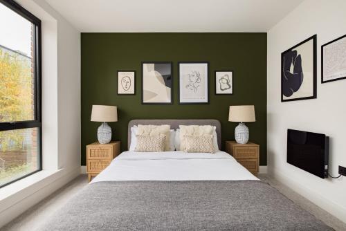 a bedroom with a bed and a green wall at The Wembley Hideout - Stylish 2BDR Flat with Balcony in London