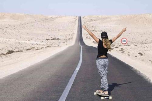 une femme qui roule sur un skateboard sur une route dans l'établissement Appartements de luxe à Al Mahdi, à Dakhla