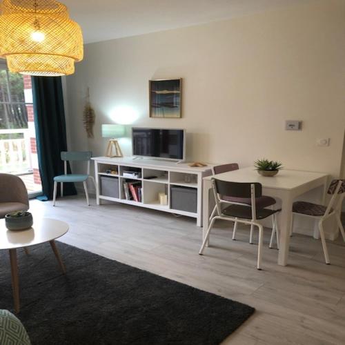 a living room with a table and a tv at Azurea - Charmant appartement à Andernos-les-Bains in Andernos-les-Bains