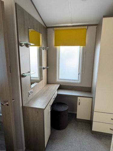 a bathroom with a vanity and a window with yellow curtains at Coastguard 45 in Whitstable