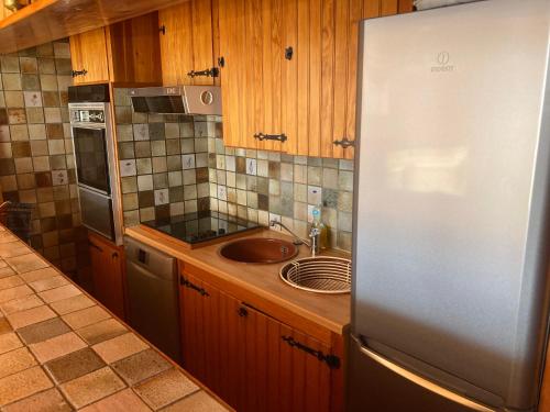 une cuisine avec un évier et un réfrigérateur dans l'établissement Très bel appartement au cœur de la station, à Orcières