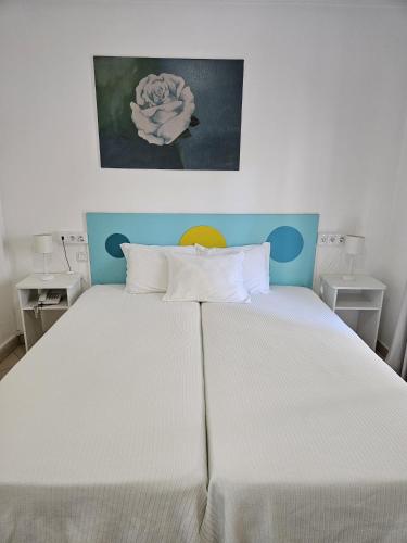 a bedroom with a large white bed with a painting on the wall at Hotel Adelaide in Faro