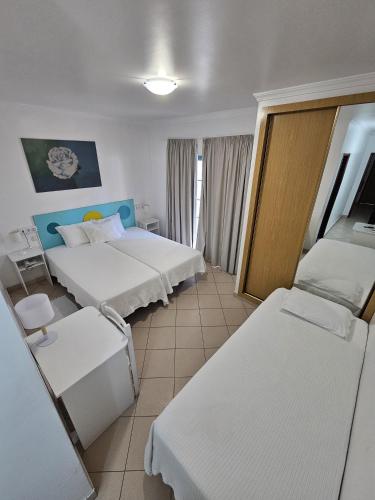 a hotel room with two beds and two chairs at Hotel Adelaide in Faro