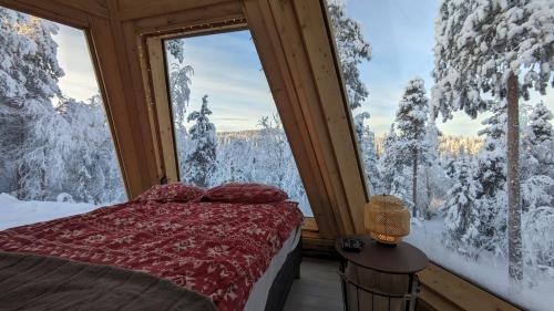 a bedroom with a bed and a view of snow covered trees at Aurora Wilderness Cones in Gällivare