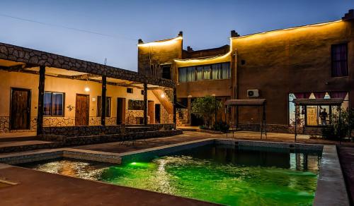 a house with a swimming pool in front of a building at Palais Ksar Lamane in Aït Ben Haddou