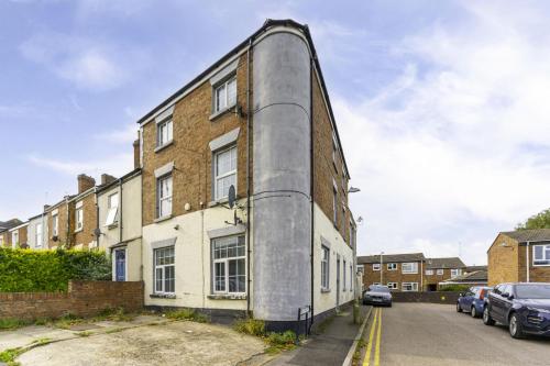 a large brick building on a street with parked cars at Comfy Stay 1 Bedroom Apartment in Rugby