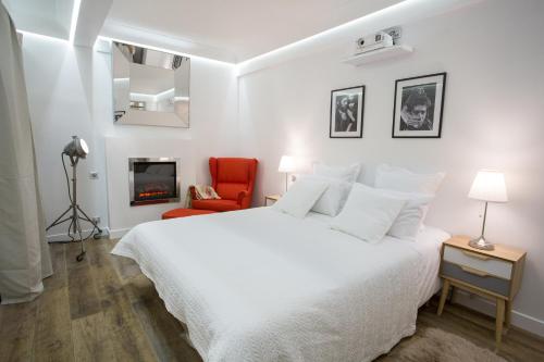 - une chambre blanche avec un lit blanc et une chaise rouge dans l'établissement Duplex cinéma face au Parc des Expositions, à Paris