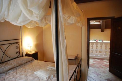 sypialnia z łóżkiem z baldachimem i lustrem w obiekcie Locanda Le Logge w mieście Urbisaglia