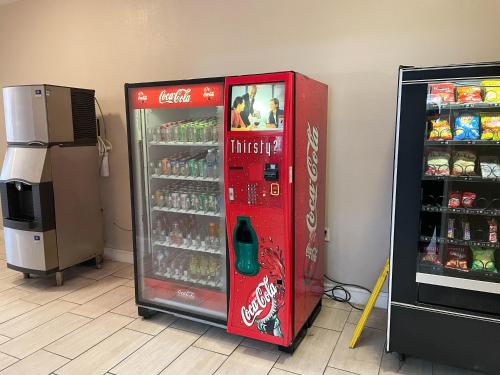 a cocacola soda machine is next to a refrigerator at Studio 6 Suites North Richland Hills TX in North Richland Hills