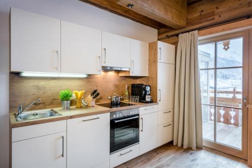 a kitchen with white cabinets and a sink and a window at Das Kleinarl in Kleinarl