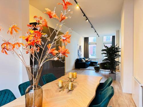 a dining room table with orange flowers in a vase at Sofia's Mansion in Breda