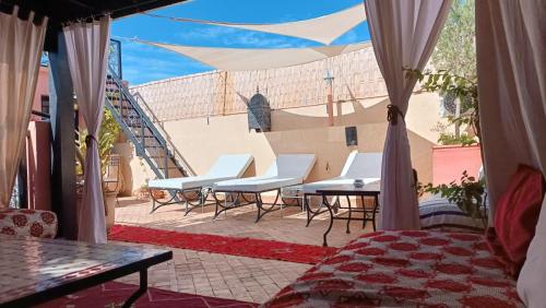 un patio con sillas, una mesa y una escalera en Riad Hugo, en Marrakech