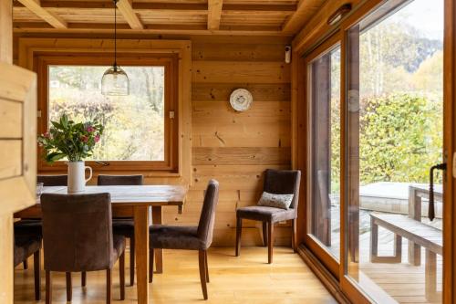 ein Esszimmer mit einem Tisch, Stühlen und einem Fenster in der Unterkunft Chalet with 5 beds 4 bath Hot Tub & Sauna - At Pangea in Les Houches