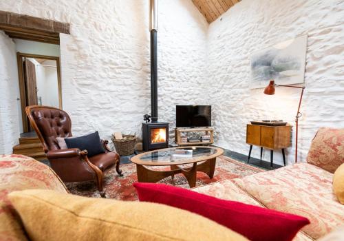 a living room with a couch and a fireplace at Ysgubor - Tranquil space for two in Saint Dogmaels