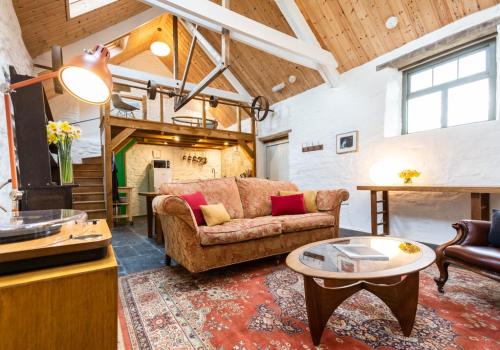 a living room with a couch and a table at Ysgubor - Tranquil space for two in Saint Dogmaels