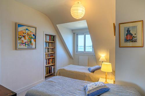 a bedroom with two beds and a book shelf at Villa Les Pieds Dans L'eau in Loctudy
