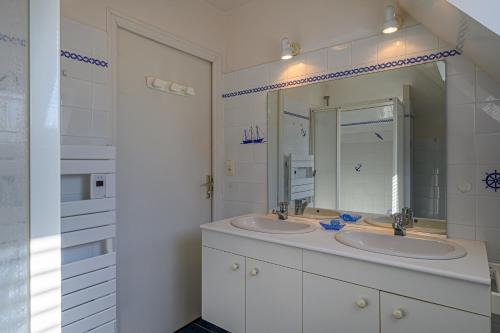 a white bathroom with two sinks and a mirror at Villa Les Pieds Dans L'eau in Loctudy