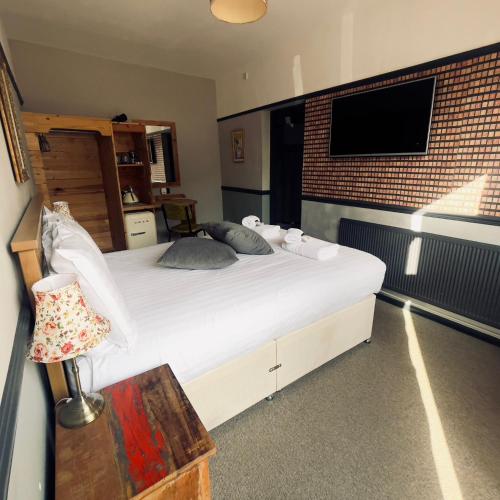 a bedroom with a large white bed with a brick wall at THE ITALIAN GREYHOUND in Great Glen